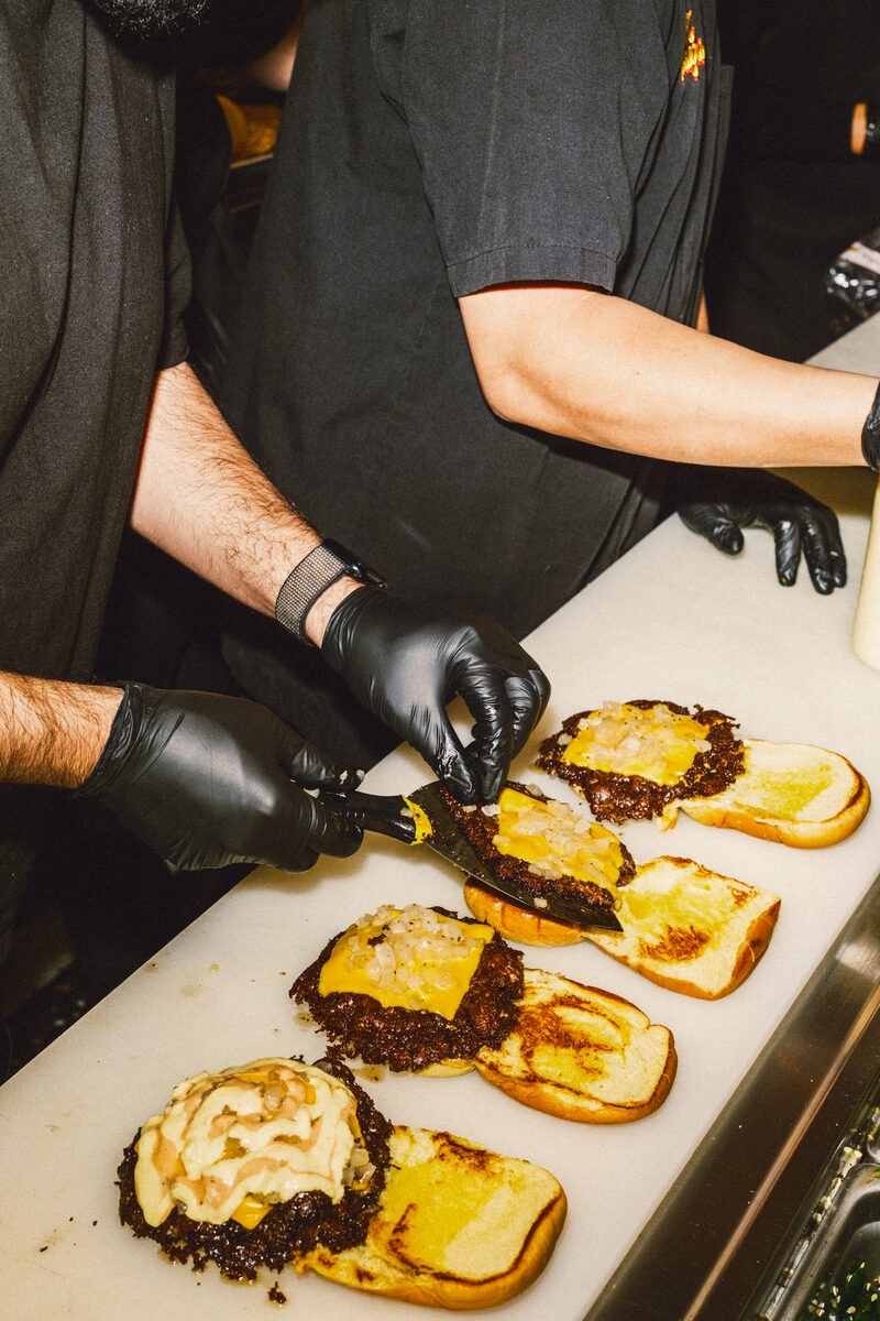 Burger Bodega smash burgers being assembled with melted cheese and toasted buns