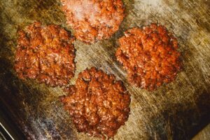 Smash burger patties developing crispy edges on the Burger Bodega flat-top in Houston