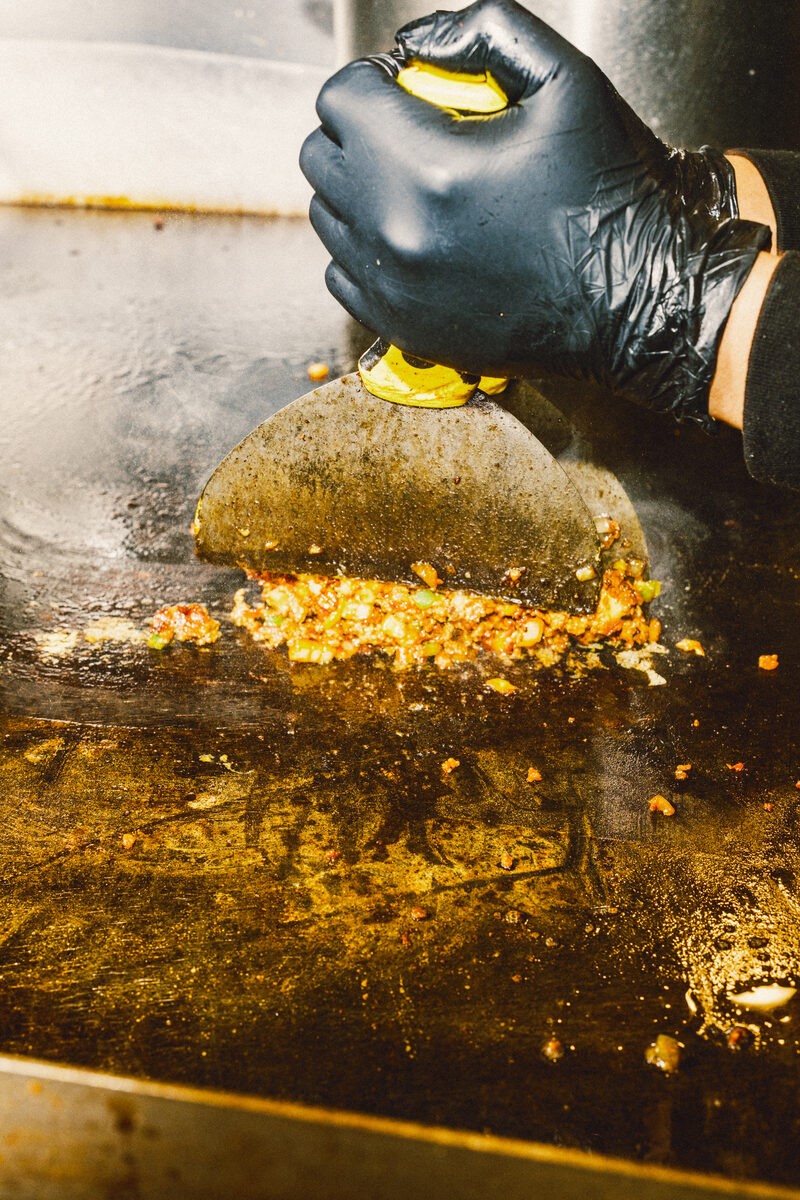 Steam rising as fresh beef is smashed onto Burger Bodega’s hot flat-top grill
