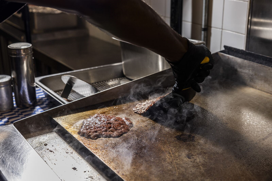 Burger Bodega chef cooking a fresh smash burger on a hot flat-top grill in Houston.