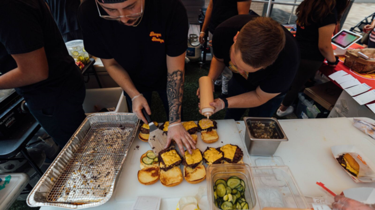 Burger Bodega team preparing fresh smash burgers on the grill during a busy service in Houston.